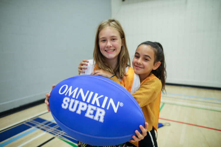 Une jeune fille tenant un ballon Omnikin Super et qui reçoit un calin d'une autre fille.